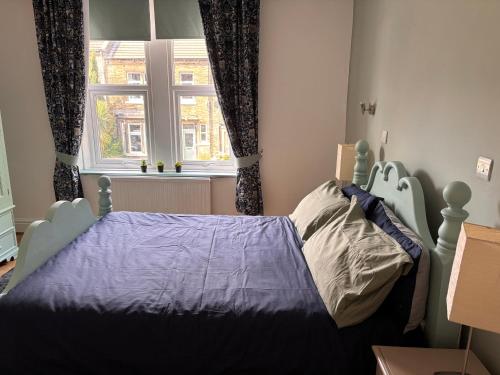a bedroom with a bed with a blue comforter and a window at Peaceful victorian house in Halifax