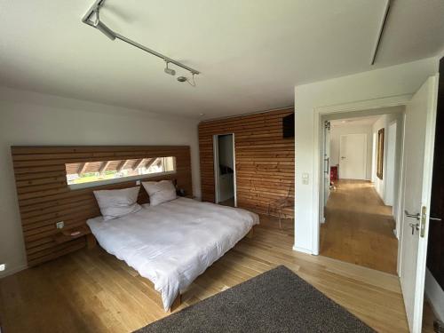 a bedroom with a white bed and a wooden wall at FerienLoft Eifeel Good - Natururlaub in Monschau in Monschau