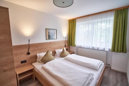 a bedroom with a bed with white sheets and a window at Appartements Pungg in Fügen