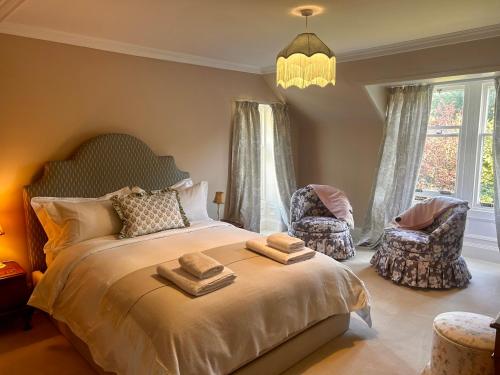 a bedroom with a large bed with two chairs and a chandelier at Clashmore House in Dornoch