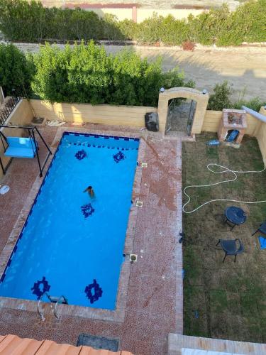 an overhead view of a large blue swimming pool at ڤيلا في الساحل الشمالي in Borg El Arab