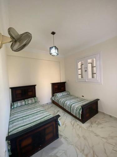 a bedroom with two beds and a ceiling fan at ڤيلا في الساحل الشمالي in Borg El Arab