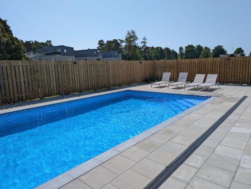a swimming pool with two chairs and a fence at Cozy, designed, Beach House apartment in Beddinge Strand