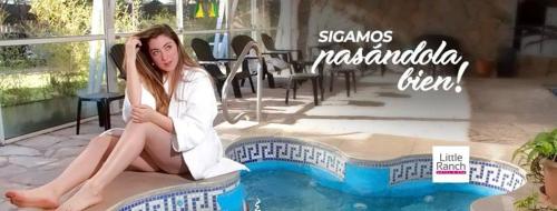 a woman sitting on the edge of a swimming pool at Little Ranch Hotel Spa Pilar in Manuel Alberti