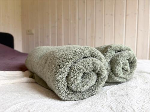 - une pile de serviettes de toilette sur le lit dans l'établissement Rātes Krasti - PĒRLE- holiday house with sauna and lakeview, à Lejasciems
