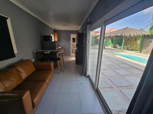 a living room with a couch and a sliding glass door at Pista Q hostel and apartments in Oranjestad