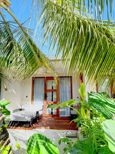 a room with a bed and some palm trees at Raakani Dhigurah in Dhigurah