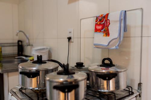 three pots on a stove in a kitchen at Casa Alegria piscina churrasqueira in Montes Claros