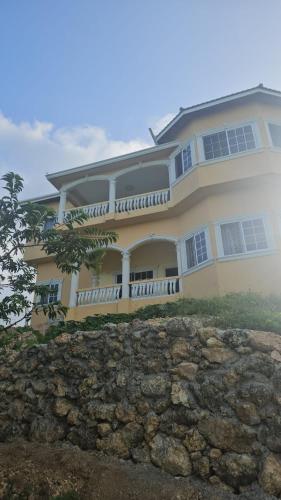 a large yellow house on top of a stone wall at Sunset grove hideaway in Port Antonio