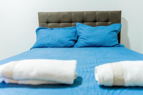 a blue bed with blue pillows and two white pillows at Casa Alegria piscina churrasqueira in Montes Claros