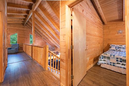 a log cabin bedroom with a bed and a balcony at Country Road Cabins in Hico