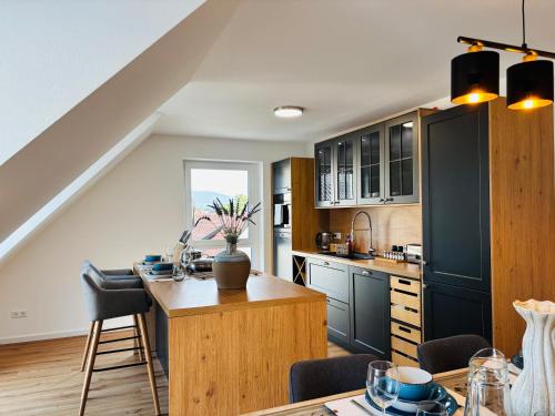 a kitchen with black cabinets and a wooden table at REMA Homes - Luxuriöse Apartments - Messenähe - Offenburg in Offenburg