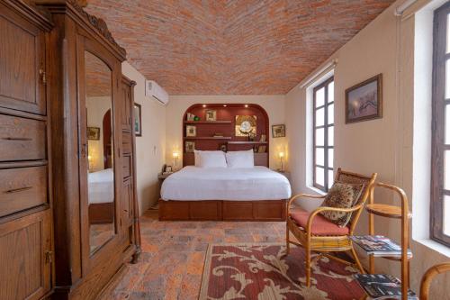 a bedroom with a large bed and a chair at Hacienda Sepulveda Hotel & Spa in Lagos de Moreno