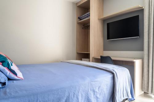 a bedroom with a bed and a flat screen tv at Elegante Ap | 3 Quartos c/Ar | 100m Praia do Forte in Škorak