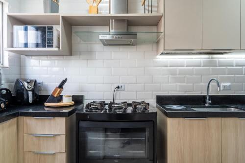 a kitchen with a stove and a sink at Elegante Ap | 3 Quartos c/Ar | 100m Praia do Forte in Škorak