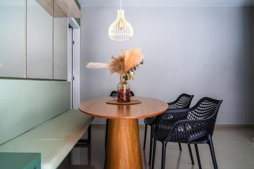 a dining room table with two chairs and a vase with feathers at Elegante Ap | 3 Quartos c/Ar | 100m Praia do Forte in Škorak