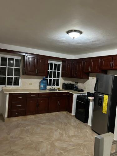 a kitchen with wooden cabinets and a black refrigerator at Villas Maniscalco in Camú