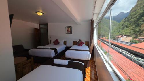a room with four beds and a window with a train at Mapi Garden's Machupicchu in Machu Picchu