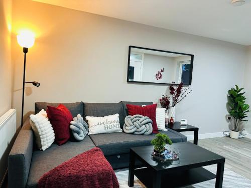 a living room with a gray couch with red pillows at Stylish 2BR Stay- Preston City in Preston
