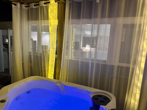 a bath tub in front of a window with curtains at Crystal Serenity Quartz Soak The Namaste Studio On Lake Hamilton in Hot Springs