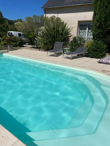 a large blue swimming pool with two chairs in a yard at Ecole de Mathuna de Marigny Brizay in Marigny-Brizay