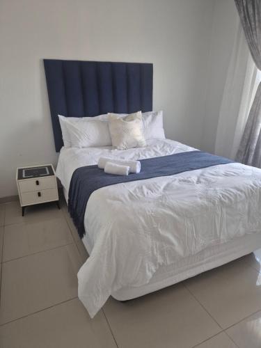 a bedroom with a large bed with a blue headboard at Charming Cottage for Getaways in Empangeni
