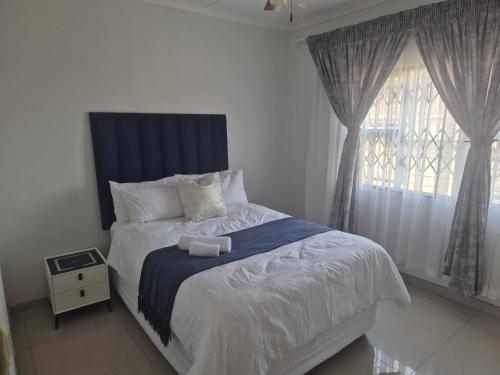 a bedroom with a bed with a blue headboard and a window at Charming Cottage for Getaways in Empangeni