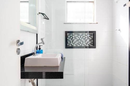 une salle de bain blanche avec lavabo et douche dans l'établissement Apartamento a 5min da Praia do Forte Luxo e Conforto, à Škorak