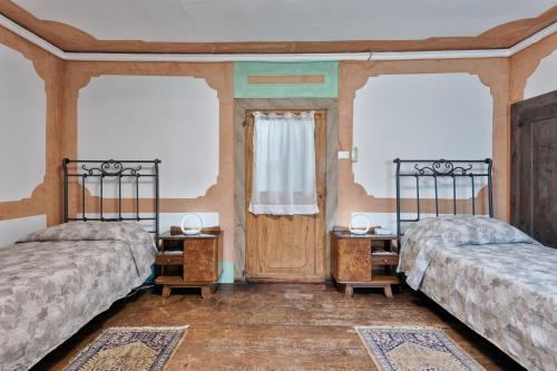 two beds in a room with two tables and a window at Country Suite 200mq in Vanzo