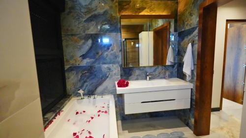 a bathroom with a sink and a bathtub with red flowers at Villa SONNE in Antalya
