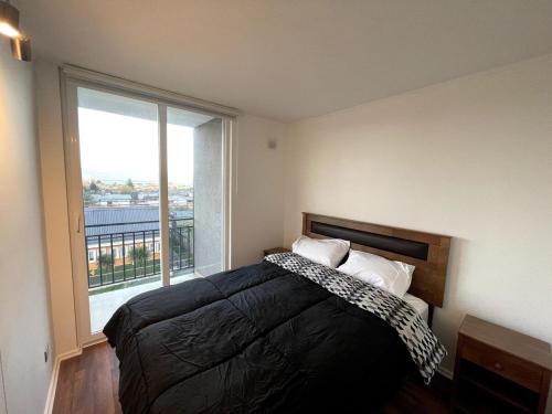 a bedroom with a bed and a large window at Cozy apartment with a view of the Volcanoes and Villarrica Lake in Villarrica