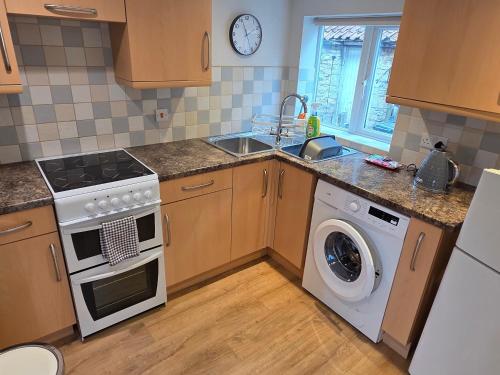 a kitchen with a stove and a sink and a dishwasher at Charming Village Cottage with Parking in Uffington