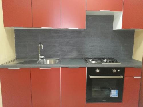 a kitchen with red cabinets and a sink at Apartment in Villa Sea Horizon Sand Beach in Cefalù