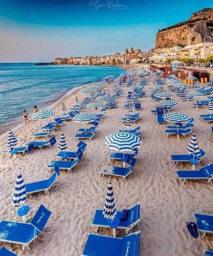 a beach filled with blue beach chairs and the ocean at Apartment in Villa Sea Horizon Sand Beach in Cefalù