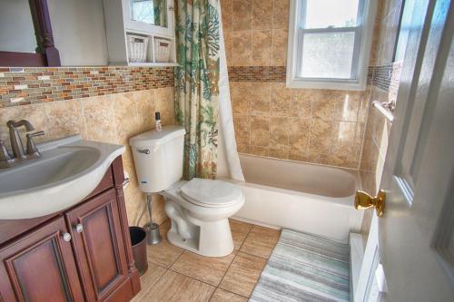 a bathroom with a toilet and a sink and a shower at Gorgeous beach house with large pool & private beach, just 3 blocks away!! in Point Pleasant Beach