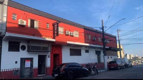 un bâtiment rouge et blanc avec des voitures garées devant lui dans l'établissement Hotel Lalique, à São Paulo