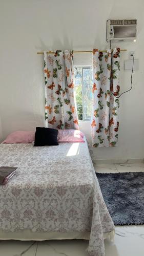 a bedroom with a bed with curtains and a window at Santana hospedagem in Cabo Frio