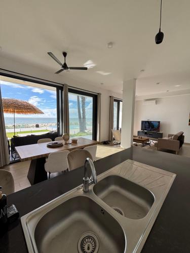 a kitchen with a sink and a living room at Stunning Oceanview 2B Waterfront Apartement in Bijilo
