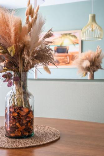 a glass vase filled with feathers and rocks on a table at Elegante Ap | 3 Quartos c/Ar | 100m Praia do Forte in Škorak