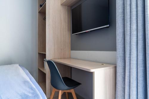 a bedroom with a desk with a tv and a chair at Elegante Ap | 3 Quartos c/Ar | 100m Praia do Forte in Škorak