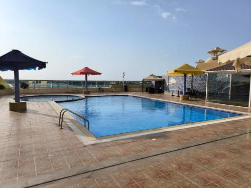 a swimming pool in a resort with an umbrella at Ilyas by Smart Home Vacation Homes in Sharjah