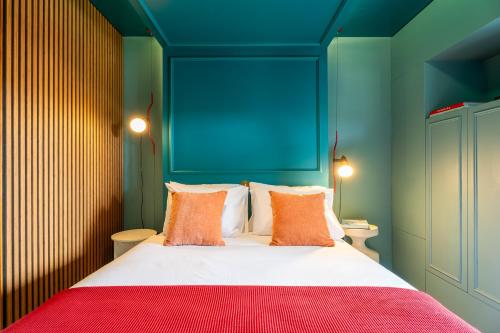 a bedroom with a bed with blue walls and orange pillows at &Tales Hotel Óbidos in Óbidos