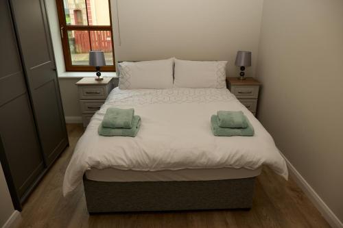 a bedroom with a large bed with two green towels on it at 12 Lurganboy Haven 