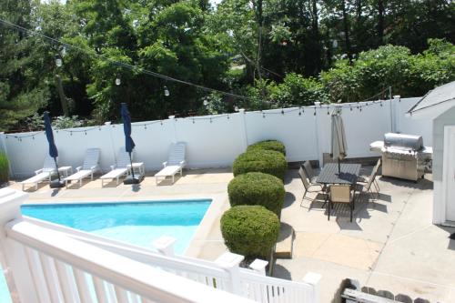 a patio with a pool and chairs and a table at Gorgeous beach house with large pool & private beach, just 3 blocks away!! in Point Pleasant Beach