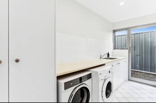 a white laundry room with a washer and dryer at Seascape on the Dunes in Sellicks Beach