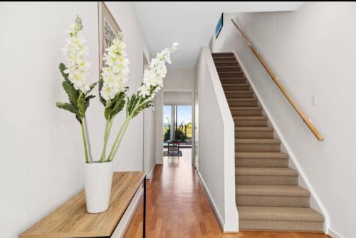 a hallway with stairs and a vase with flowers at Seascape on the Dunes in Sellicks Beach