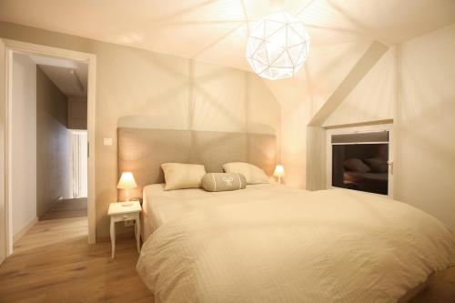 Un dormitorio con una gran cama blanca y una lámpara. en La Fermette des Fagnes, en Malmedy