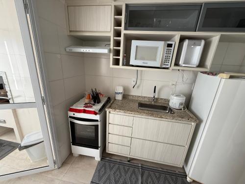 a small kitchen with a sink and a refrigerator at Lazer de resort e vista marcante in Guarujá