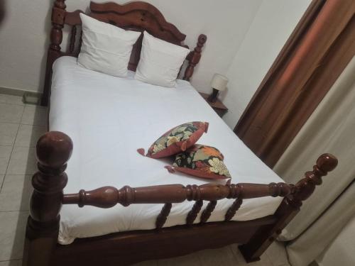 a bed with a wooden frame with two pillows on it at Appartements Des Roses in Le Lamentin