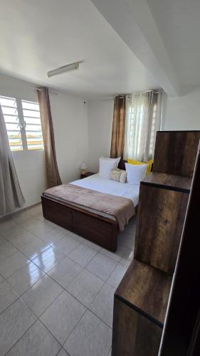 a bedroom with a bed in a room with windows at Appartements Des Roses in Le Lamentin